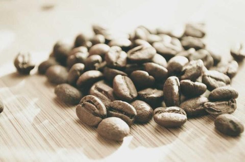 A handful of roasted coffee beans on a wooden board.